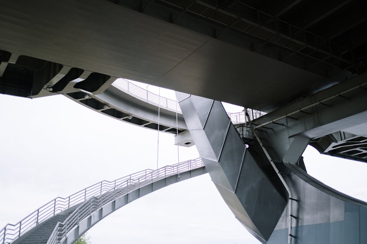 Upward view of a modern steel bridge with intricate stairs and architectural elements.